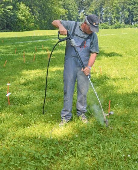 Pour traiter le rumex au champ, utilisation d'un nettoyeur à haute pression. Avec sa lance dotée d'une buse à jet rotatif, l'opérateur tourne autour du pied de chaque plante. Cette eau chaude pulvérisée creuse un trou sur les 10 cm nécessaires pour « brûler » la partie de la racine à détruire.© J.-M.V.