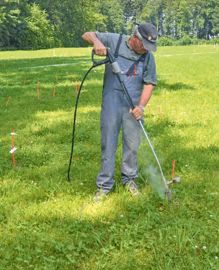 Pour traiter le rumex au champ, utilisation d'un nettoyeur à haute pression. Avec sa lance dotée d'une buse à jet rotatif, l'opérateur tourne autour du pied de chaque plante. Cette eau chaude pulvérisée creuse un trou sur les 10 cm nécessaires pour « brûler » la partie de la racine à détruire.© J.-M.V.
