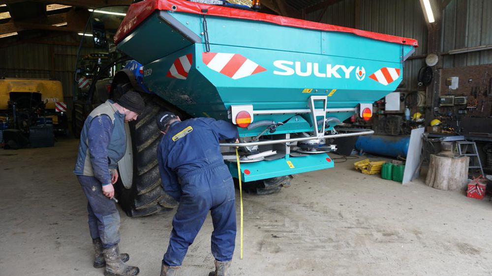 Théo Gorieux prépare un distributeur d’engrais Sulky DX30+ avant le chantier d’épandage, avec l’appui de son père, Patrick.