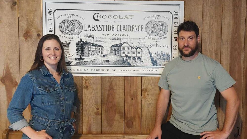 Anaïs Le Calvez et Gabriel Auzi devant une reproduction de l'emballage originel du chocolat crée par Jules Auzi en 1903.