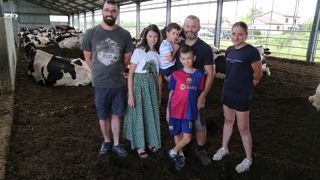 En été, l'aire malaxée des vaches est toujours sèche. Baptiste Dessapt au centre avec ses trois enfants (Louise à gauche, Malo dans ses bras et Robin) ne regrette pas son choix innovant. Clément Charles (à gauche) et Laurine Renaud (à droite) les deux salariés de l'exploitation apprécient aussi de travailler dans ces conditions.