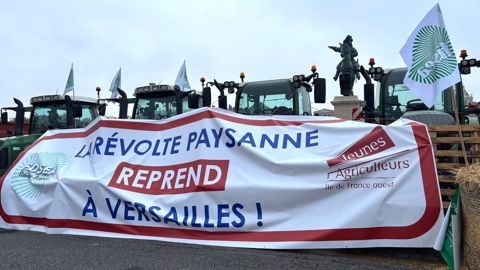 Une banderole déployée devant la place d'Armes du château de Versailles.