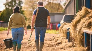 Viel éleveur et jeune éleveuse près d'un bâtiment