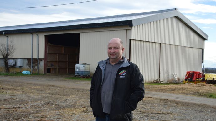 Gérard Roman devant la grange qu’il a équipée de panneaux photovoltaïques bi-verre, qui permettent le séchage du foin.